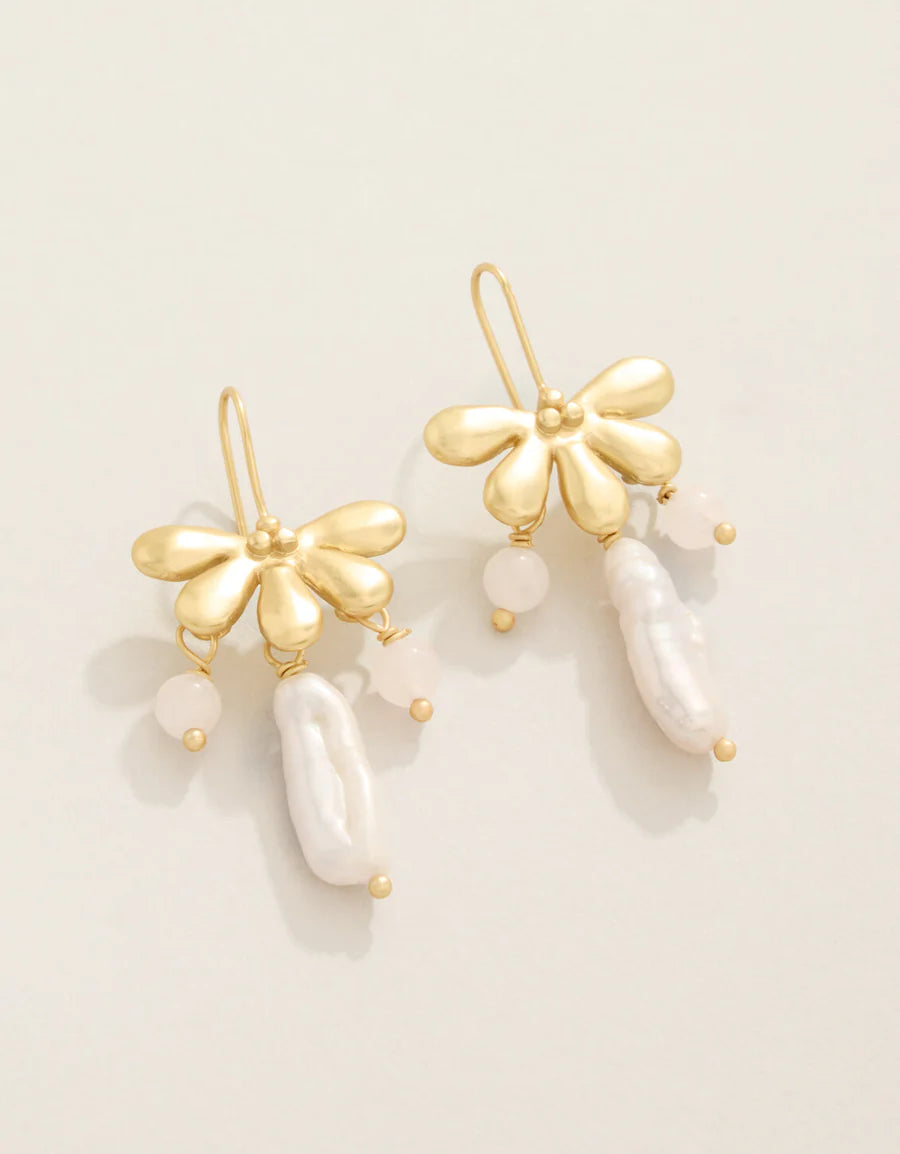Gold earrings with pearl-like beads on a light beige background