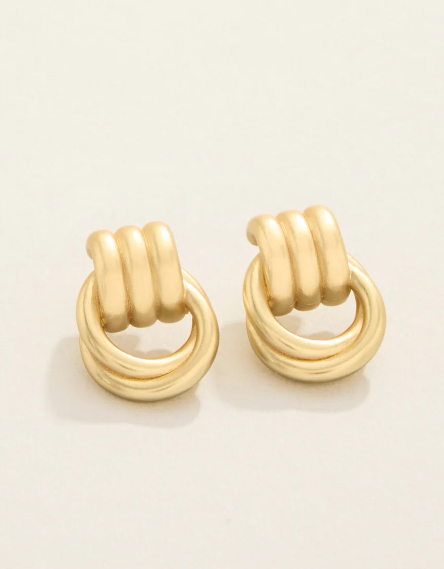 Pair of gold hoop earrings on a beige background