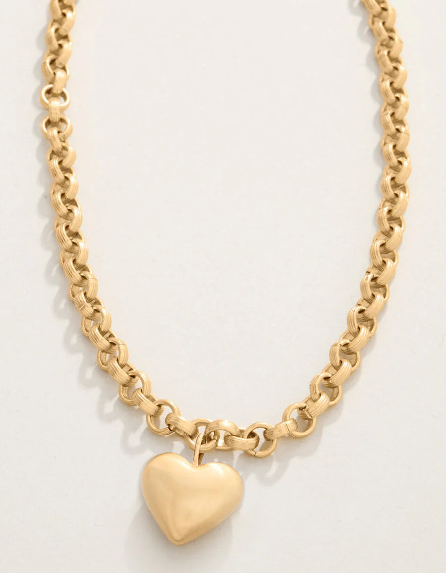 Gold chain necklace with a heart pendant on a light gray background