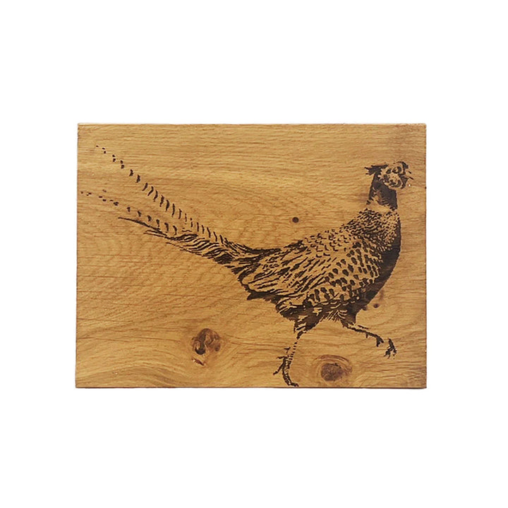 Wooden cutting board with a engraved pheasant design on a white background