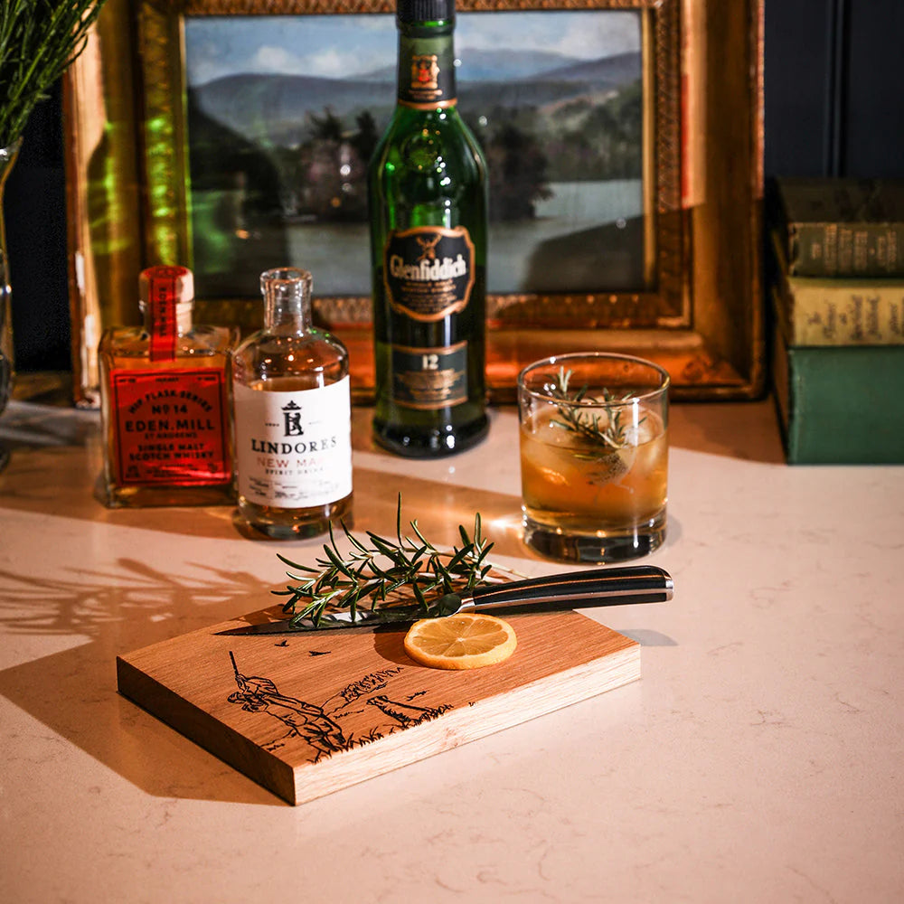 Alcohol bottles and a cocktail on a wooden coaster with a scenic background