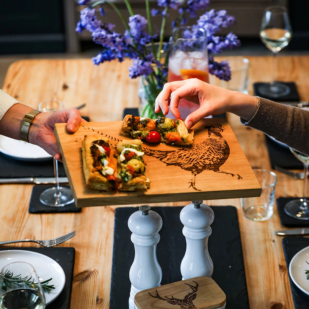 Two people sharing a wooden board with food on a dining table.