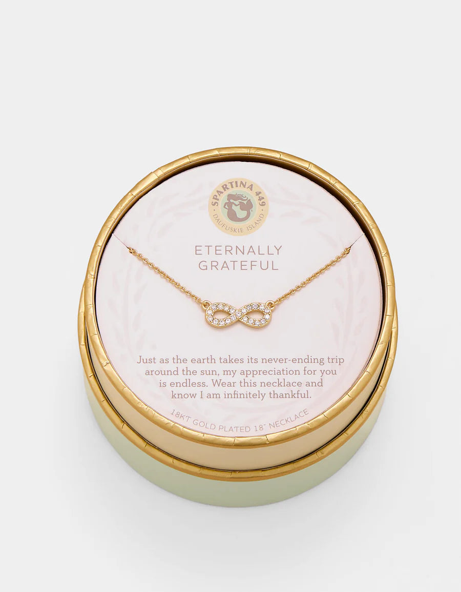 Gold necklace in a round, gold box with a message card on a white background
