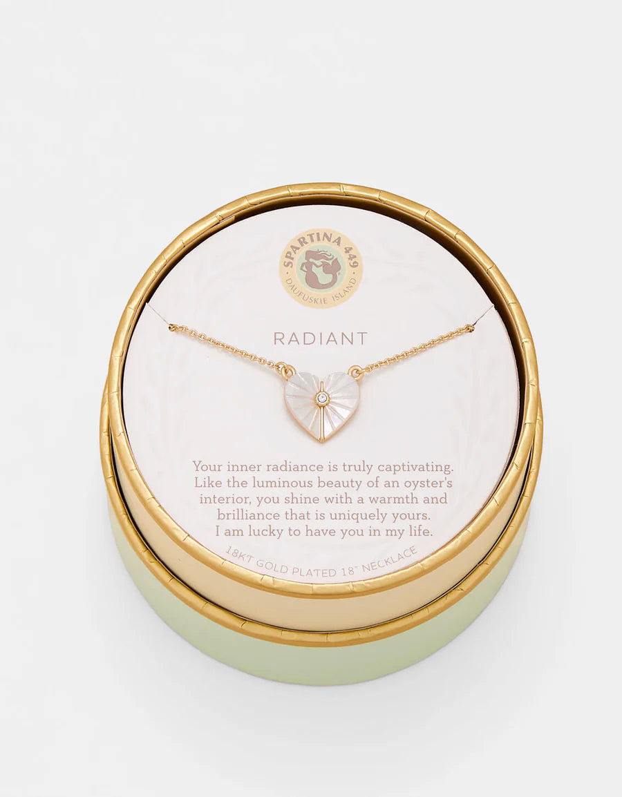 Gold necklace in a round gold box with a message card on a white background