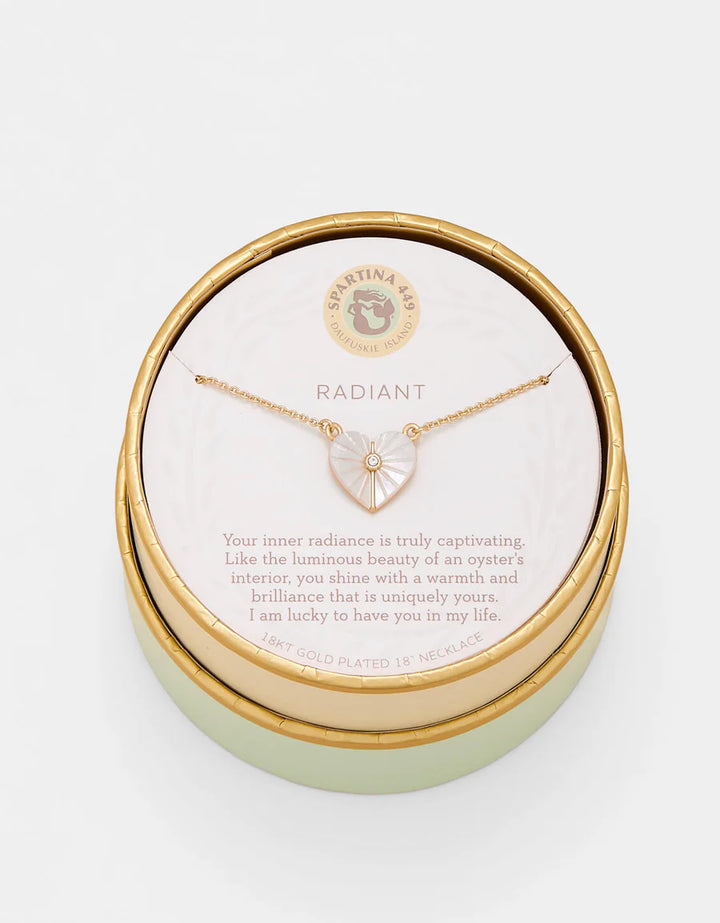 Gold necklace in a round gold box with a message card on a white background