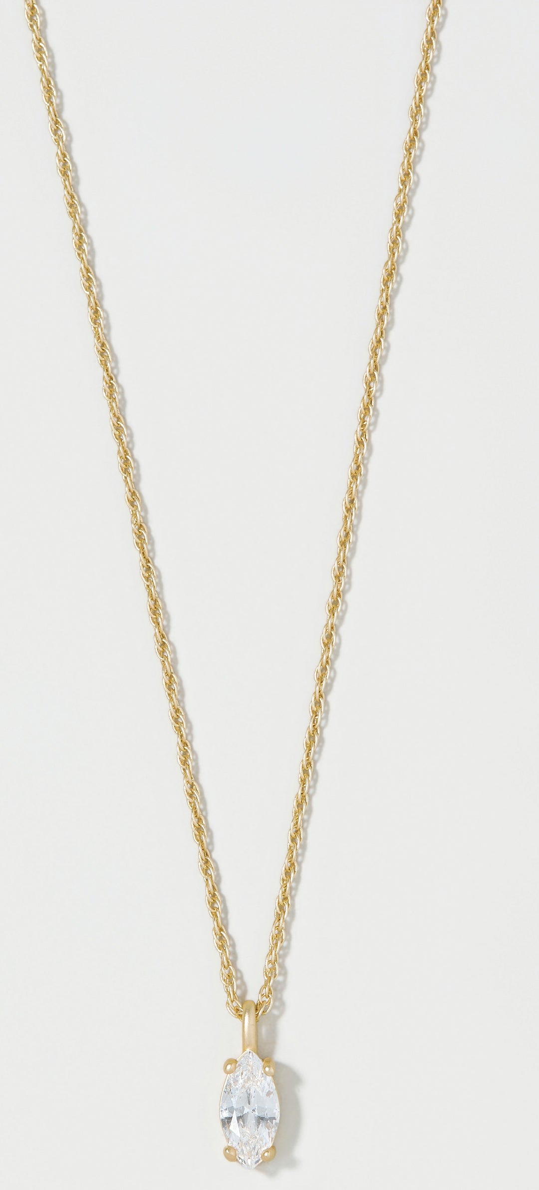 A gold chain necklace with a small gold bail holding a marquise-cut clear gemstone, shown against a light gray background.
