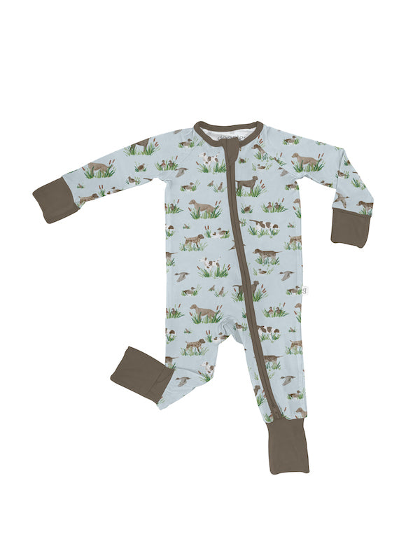 long-sleeve footed sleeper with a light blue-green background, brown trim, and a woodland animal print, photographed against a white studio background.