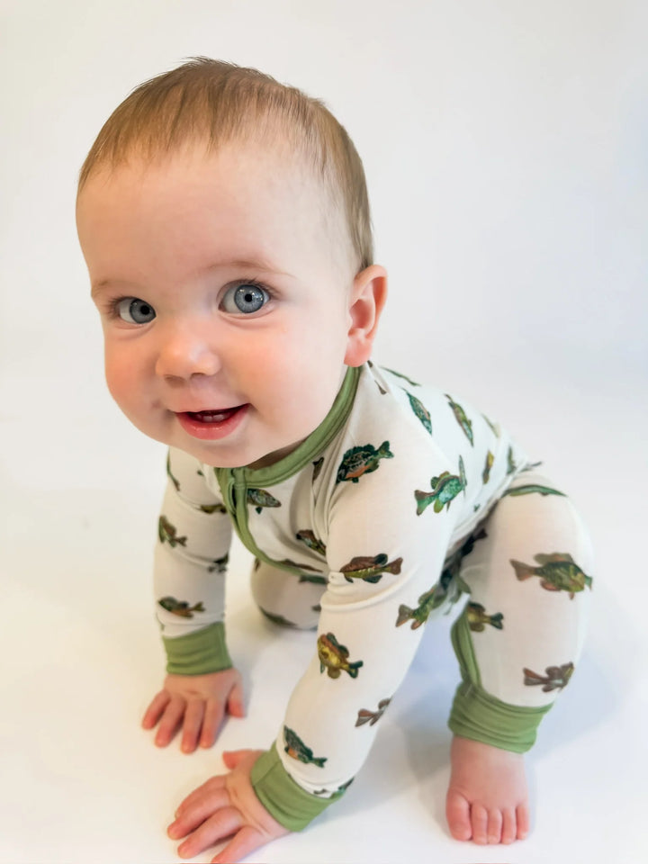 Baby wearing a white onesie with green fish pattern on a white background