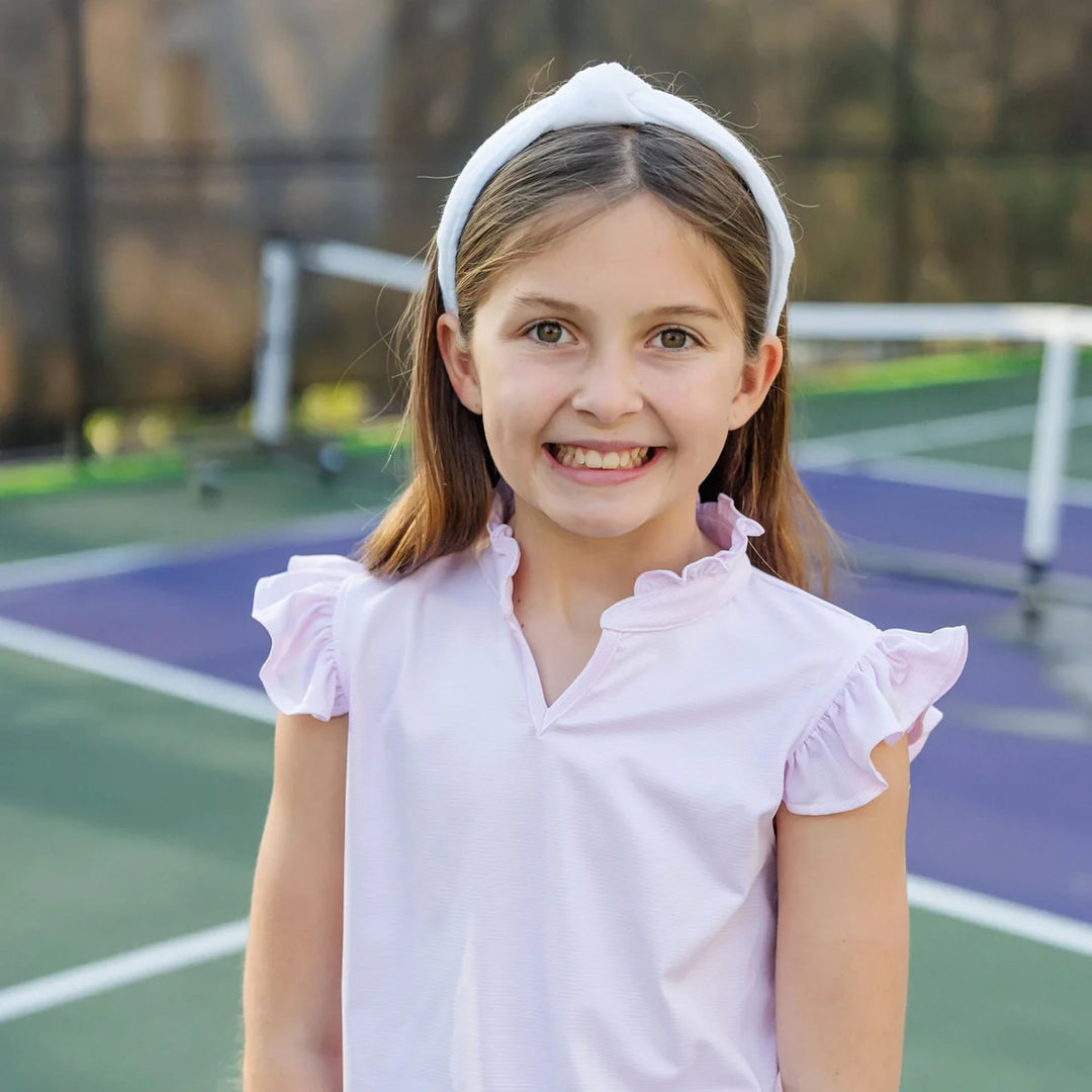 Young girl in a pink shirt on a tennis court