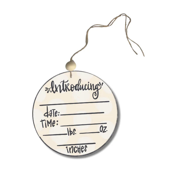 Round wooden baby announcement tag with text fields on a white background