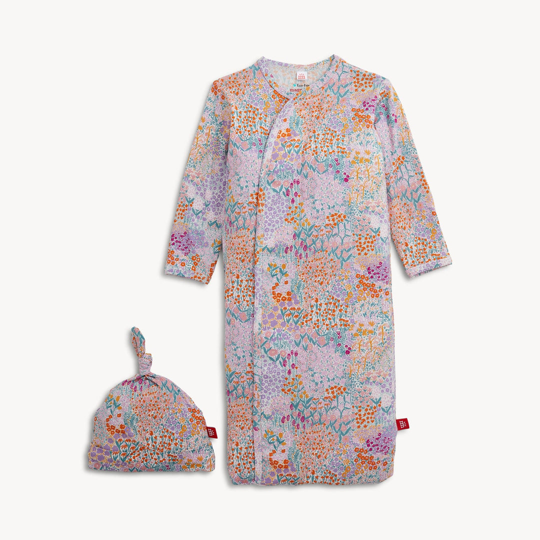 A baby sleep sack and matching beanie set with a colorful floral and abstract print on a light lavender-gray background, displayed on a clean off-white background.