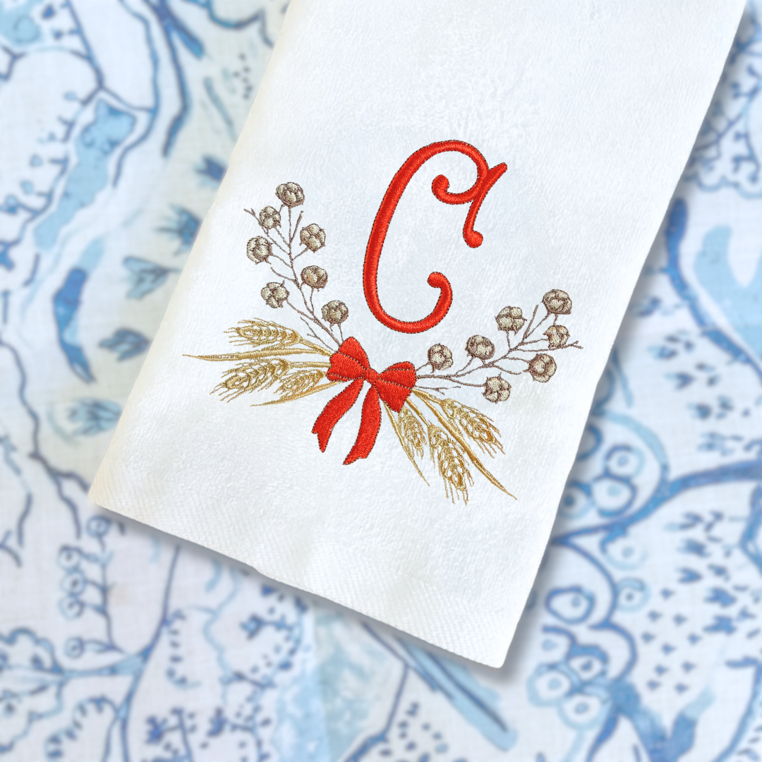 White napkin with orange letter 'C' and wheat design on a blue patterned background