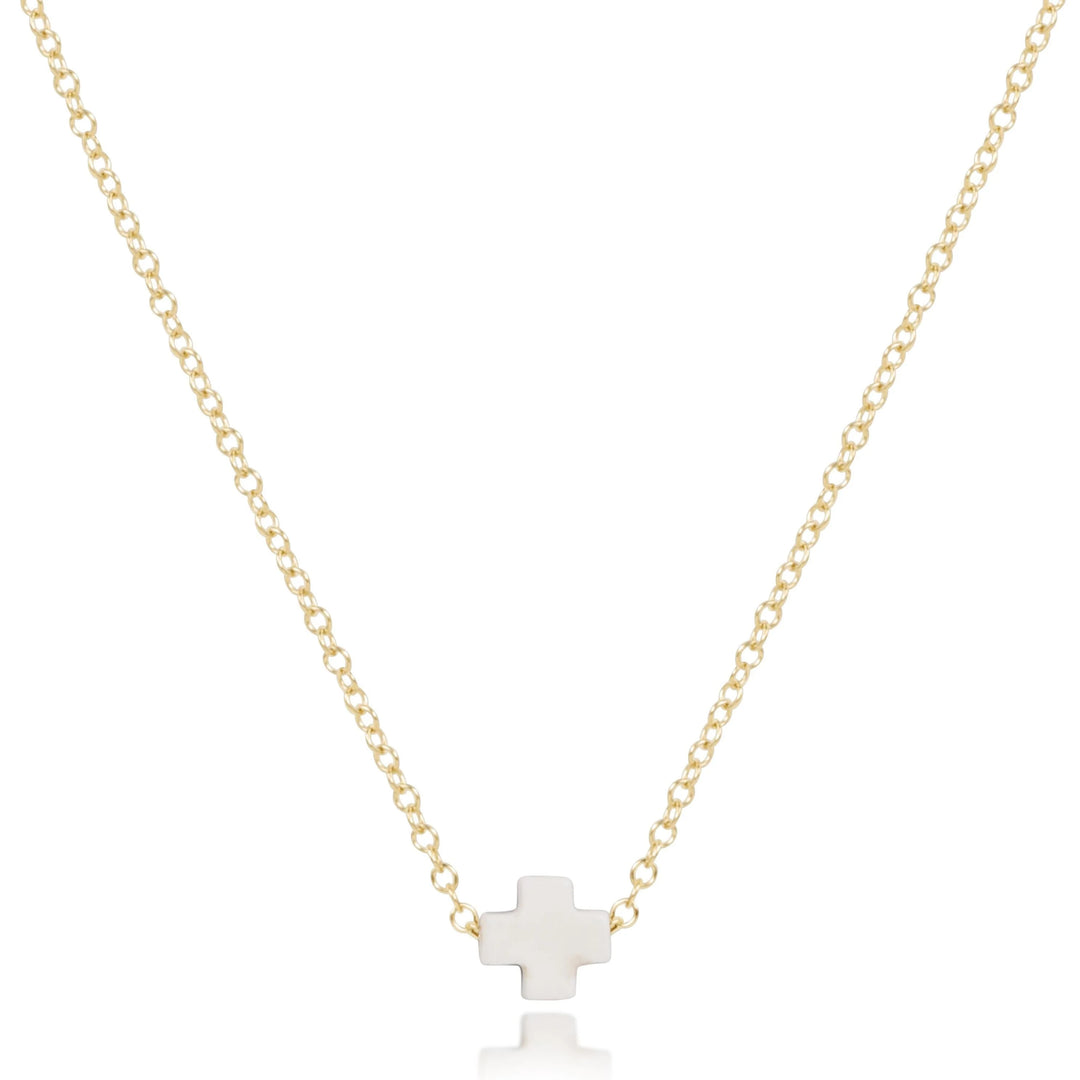 Gold necklace with an off white cross pendant on a white background