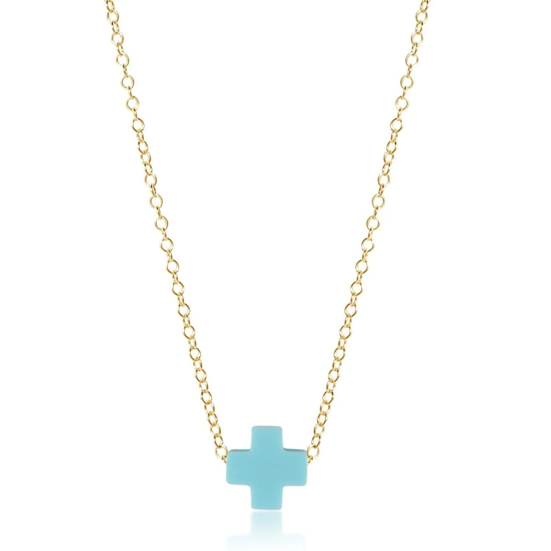 Gold necklace with a turquoise cross pendant on a white background