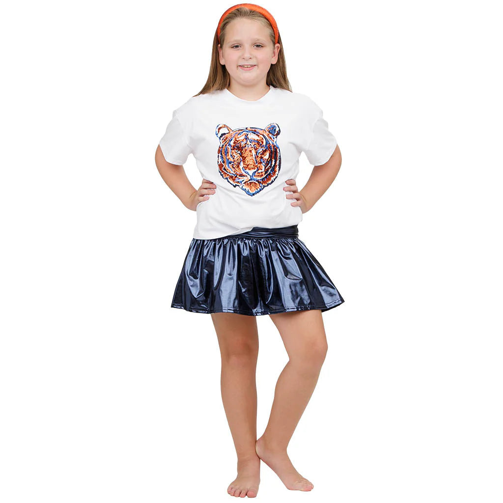 Young girl wearing a white t-shirt with a tiger design and a black skirt on a white background