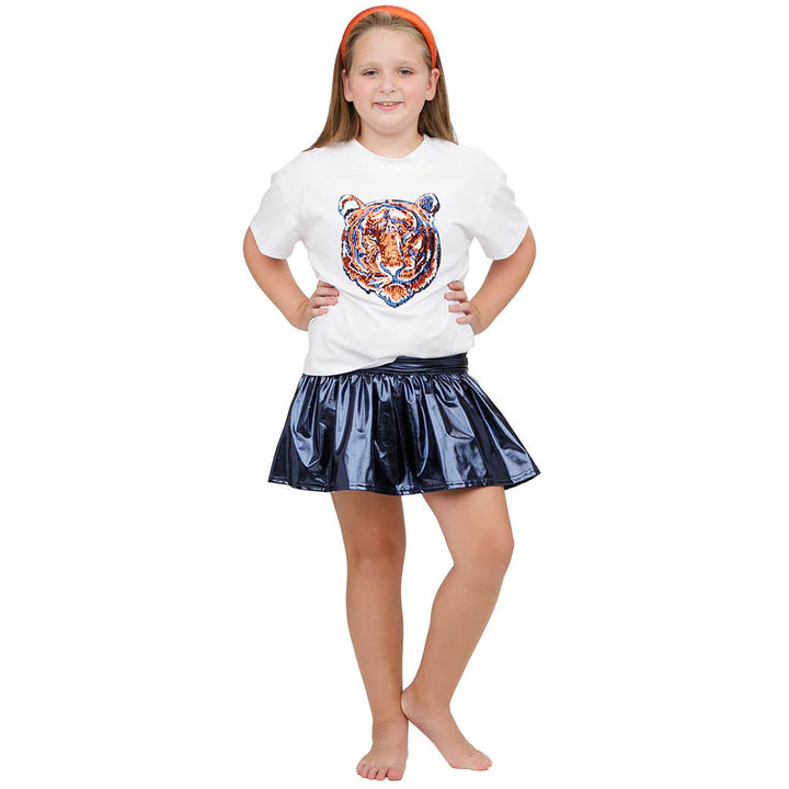 Young girl wearing a white t-shirt with a tiger design and a black skirt on a white background