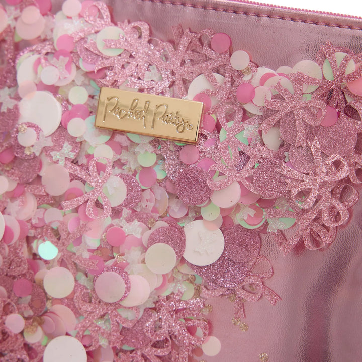 Pink decorative item with glittery elements and a gold tag on a pink background
