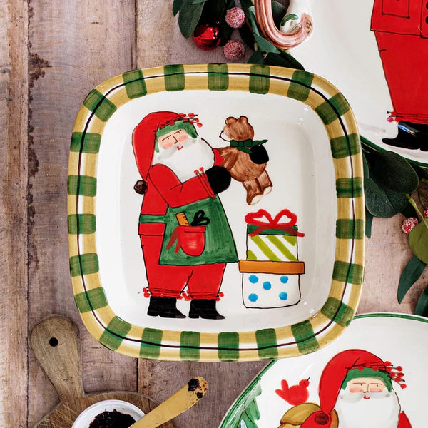 Decorative plate with Santa Claus holding a teddy bear and gift, on a wooden surface.