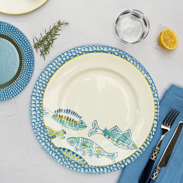 Decorative plate with fish design on a table setting with cutlery and lemon.