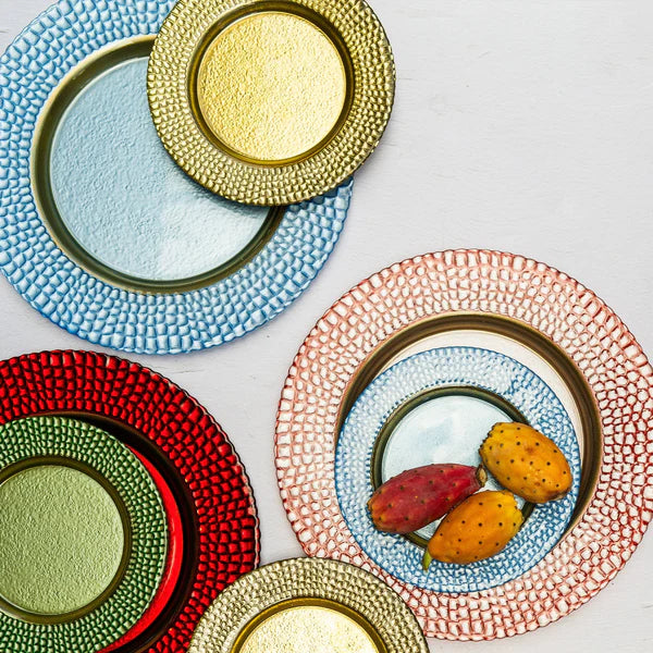 Set of colorful textured plates with a focus on a pink plate with fruits.
