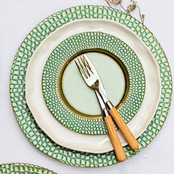 Set of green and white ceramic plates with a fork on a light background