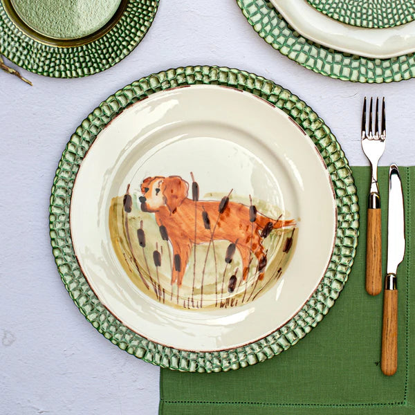 Dinner setting with a plate featuring a dog illustration on a green tablecloth.