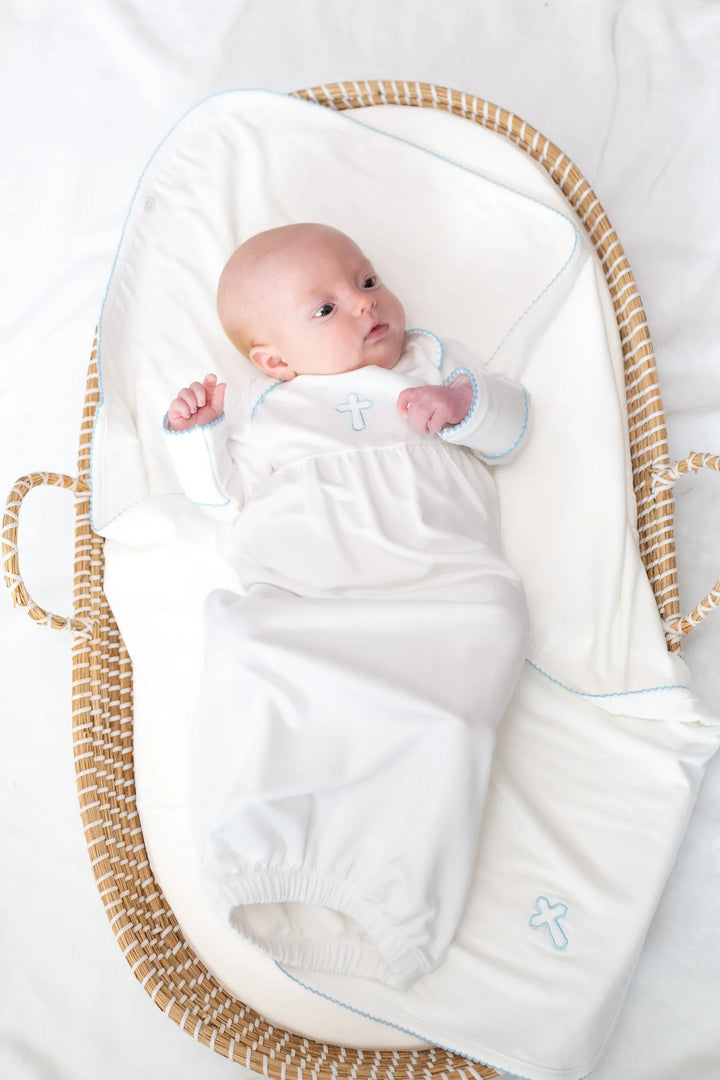 Newborn baby wrapped in a white blanket with blue accents, lying in a wicker Moses basket.