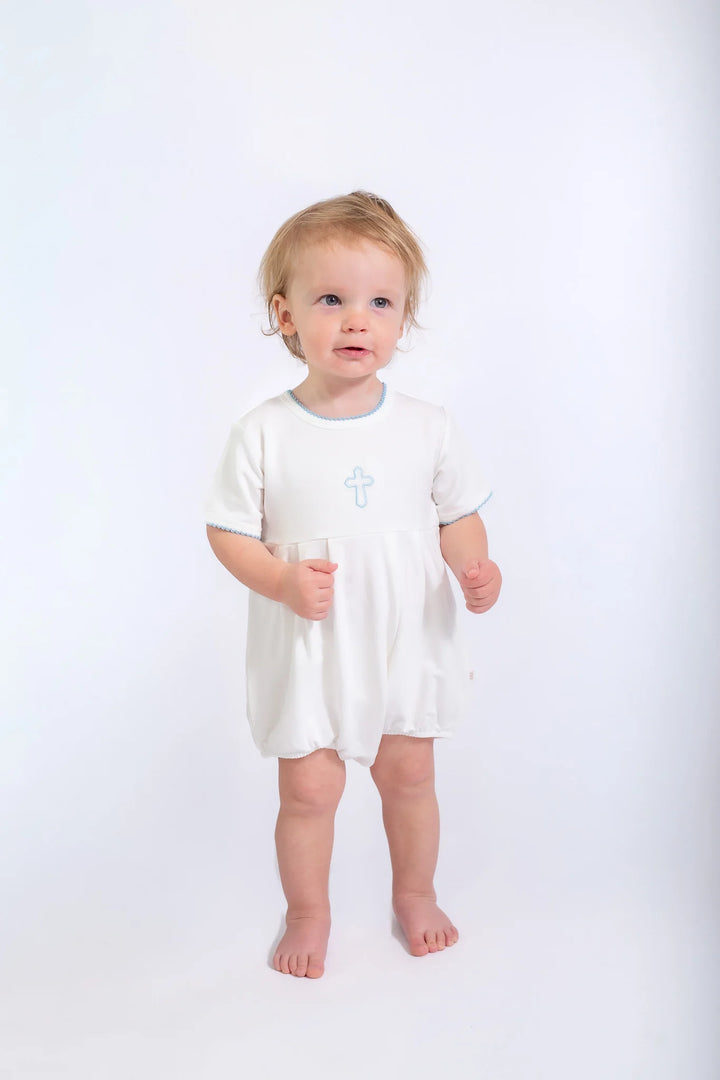 Child wearing a white onesie with a blue cross on a white background
