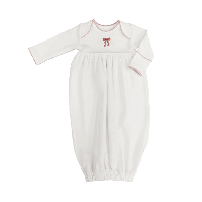 White baby gown with red trim and bow on a white background