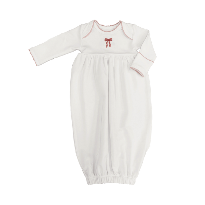 White baby gown with red trim and bow on a white background
