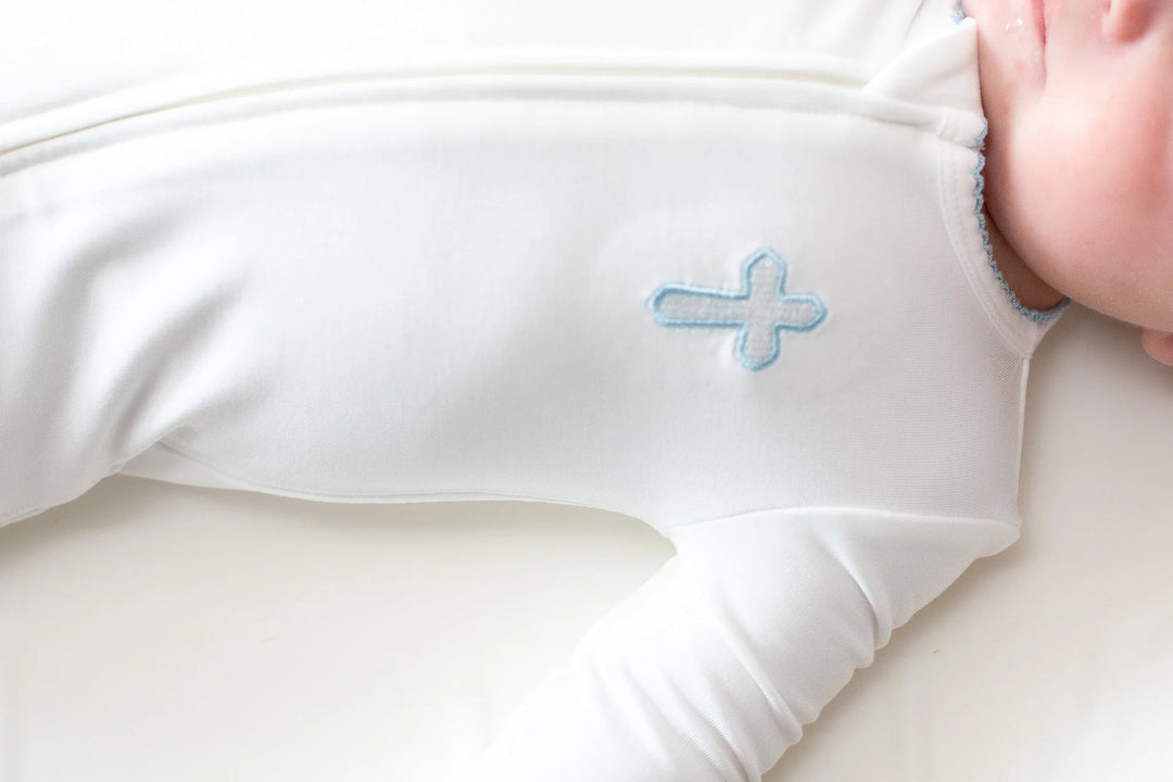 Close-up of a baby's arm in a white sleeve with a blue flower design on a white background