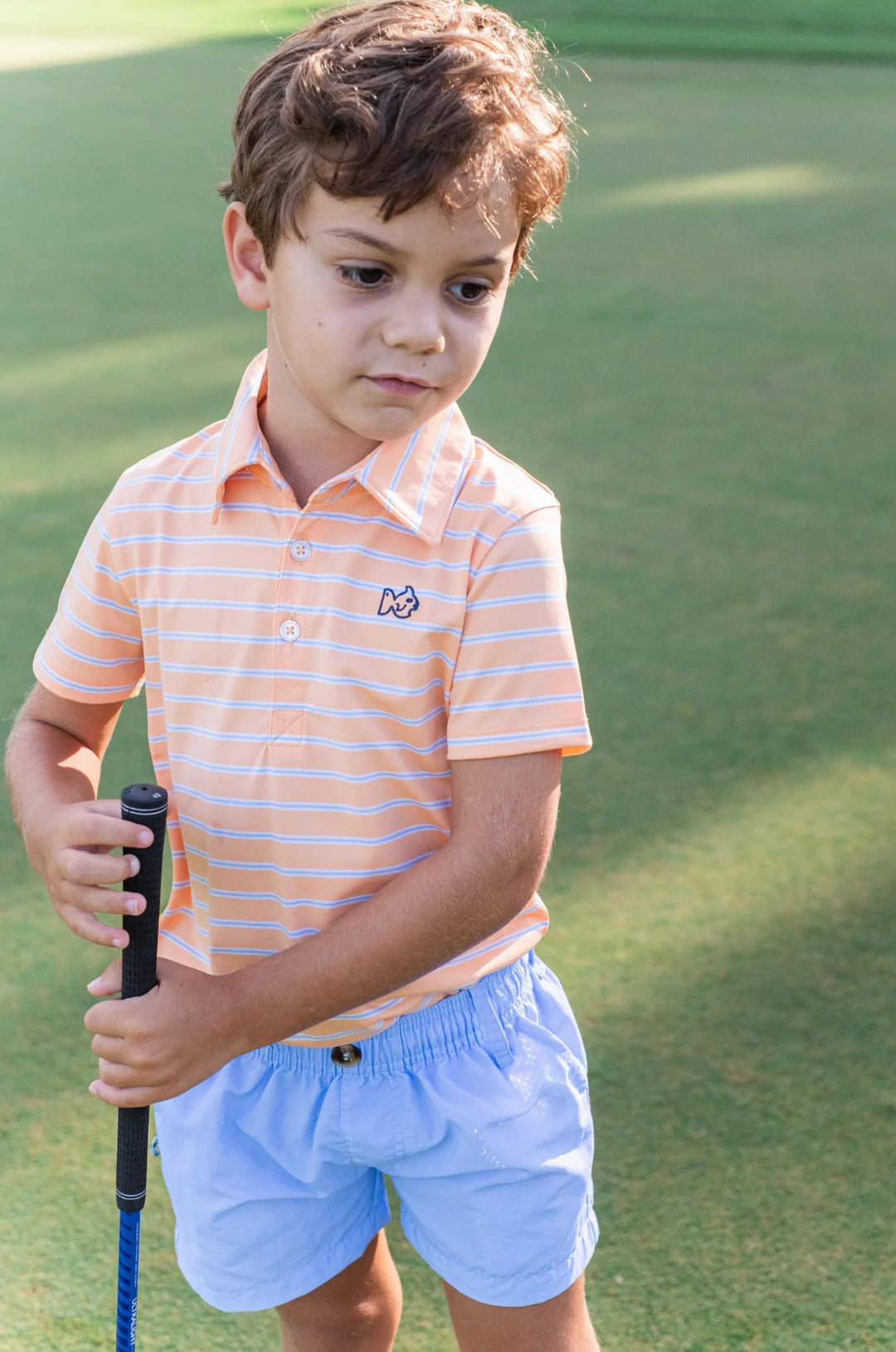 LITTLE BOY AT GOLF COURSE WEARING ORANGE AND  BLUE STRIPE BOYS SHORT SLEEVE POLO WITH COLLAR