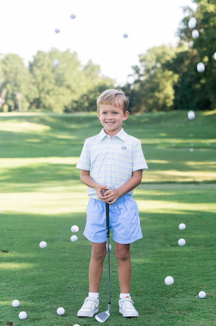 LITTLE BOY ON GOLF COURSE SURRONDED BY GOLF BALLS WEARING YELLOW AND  BLUE STRIPE BOYS SHORT SLEEVE POLO WITH COLLAR