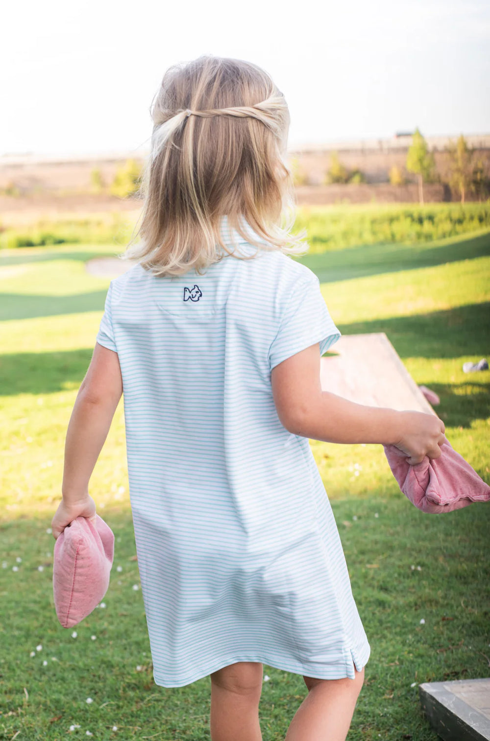 little girl wearing light blue and white striped girls short sleeve polo dress on grass