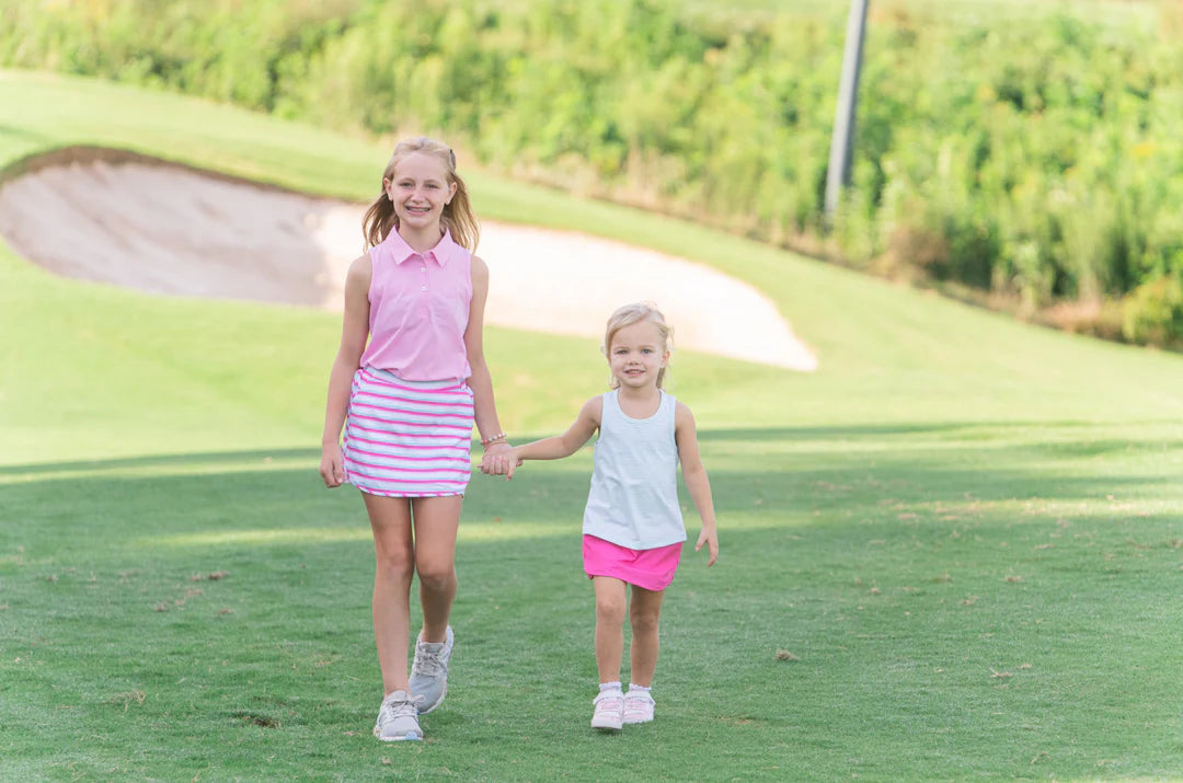 TWO GIRLS HOLDING HANDS WALKING ON GOLF COURSE