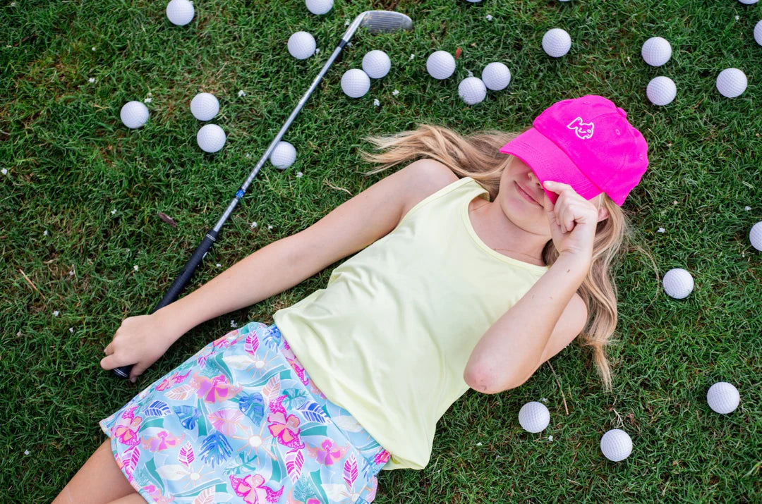 GIRLS LAYING ON GRASS WEARING PINK HAT AND YELLOW TANK