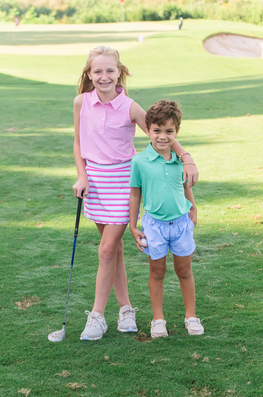 GIRL AND BOY ON GOLF COURSE WEARING GOLF OUTFITS