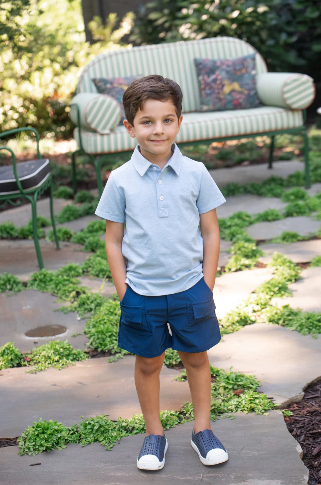 LITTLE BOY WEARING NAVY BLUE SHORTS STANDING IN YARD