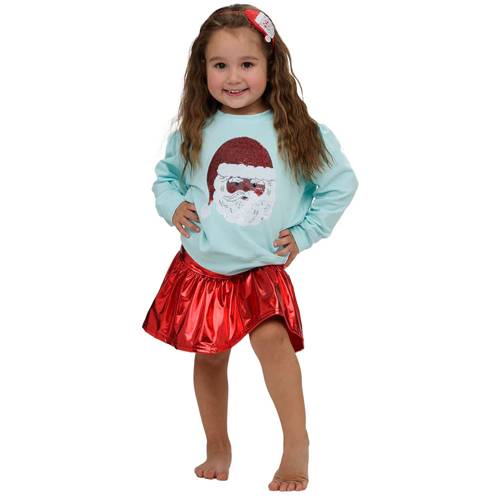 Child wearing a light blue sweater with a Santa Claus design and a red skirt on a white background.