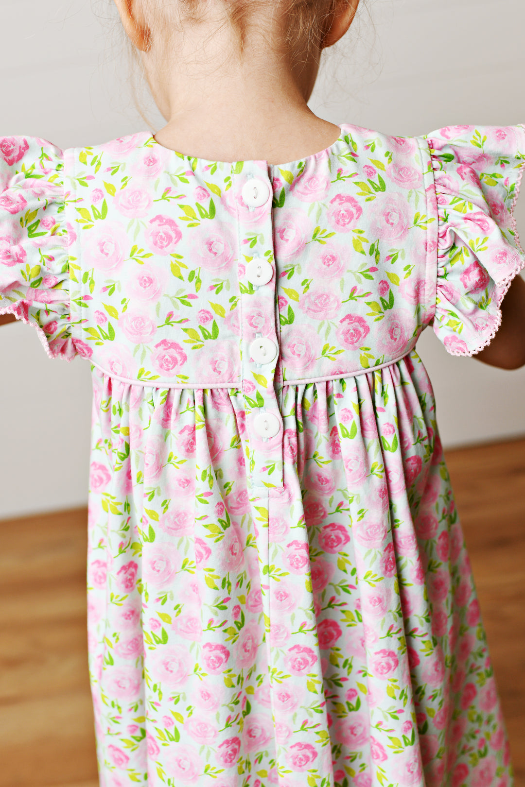 Child wearing a pink floral dress with ruffled sleeves.