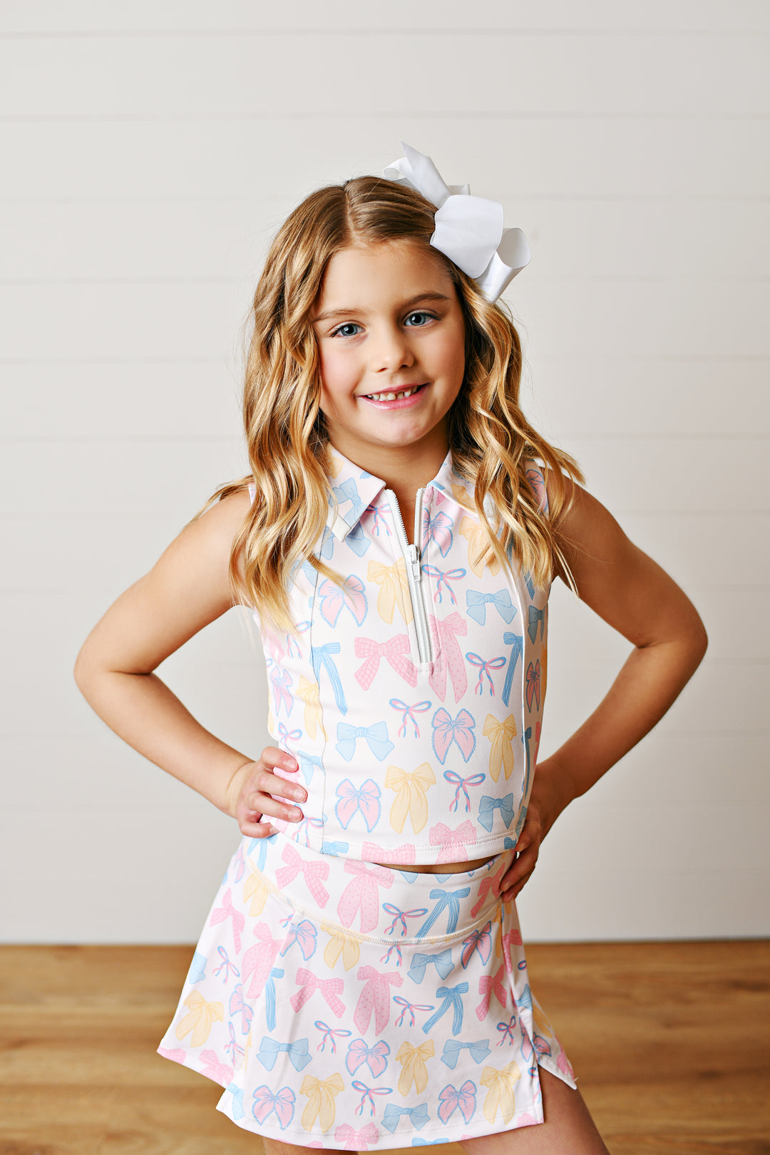 Allover spring bow print with preppy charm
Two-piece collared tank and; skort set on little girl with white bow in hair