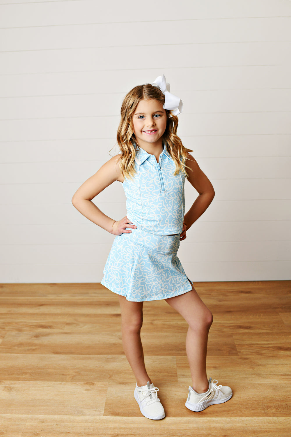 Allover sky-blue bow print with preppy appeal
Two-piece collared tank and; skort set on little girl with white bow in her hair