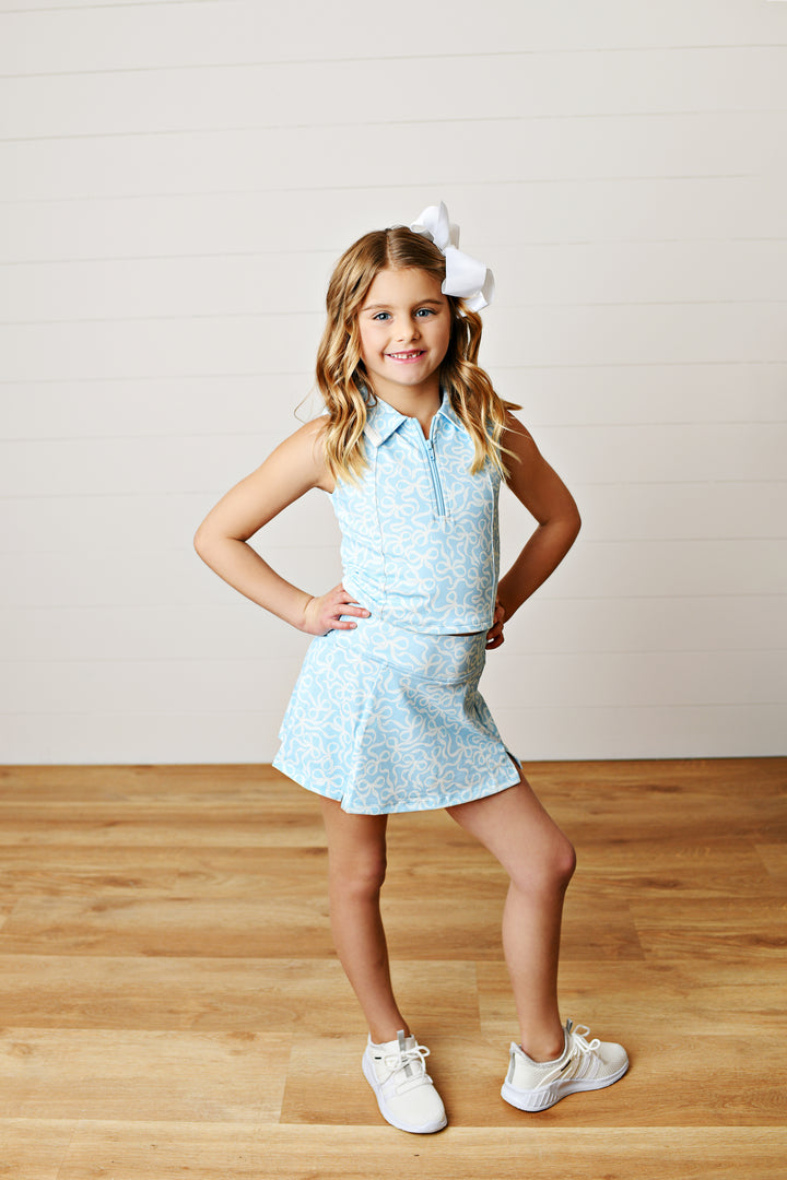 Allover sky-blue bow print with preppy appeal
Two-piece collared tank and; skort set on little girl with white bow in her hair