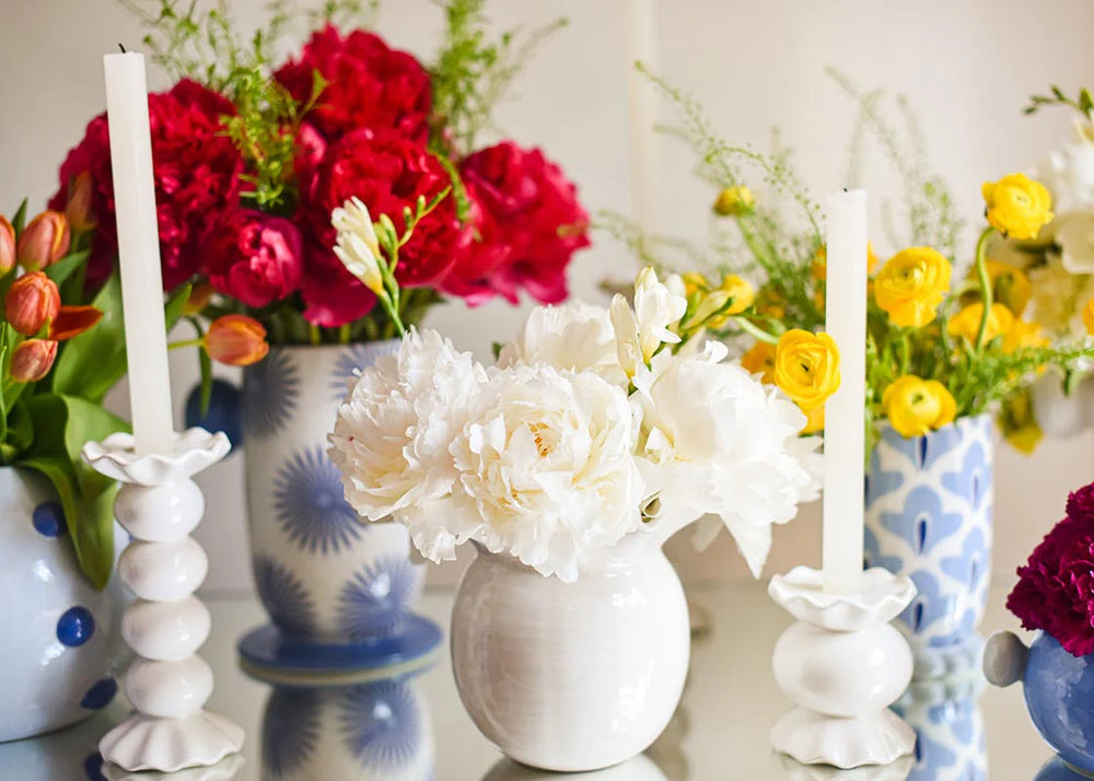 Decorative setup with flowers, candles, and vases on a reflective surface.