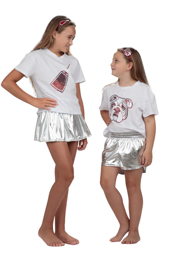 Two young girls wearing matching outfits with graphic tees and silver skirts on a white background