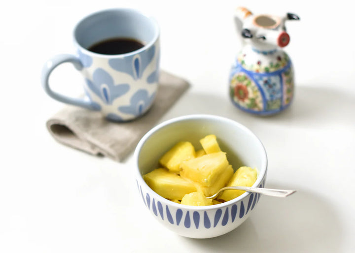 Bowl of pineapple with a cup of coffee and decorative item on a table