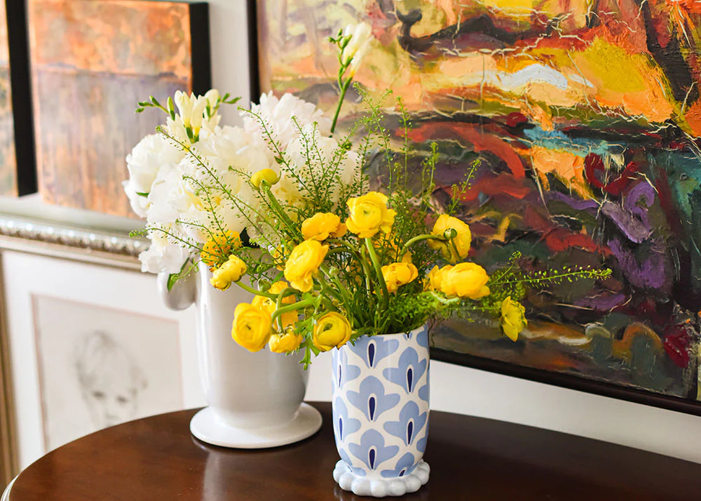Two vases with flowers on a table in front of a colorful painting