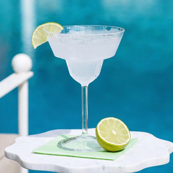 Cocktail with a lime wedge on a marble surface against a blue background