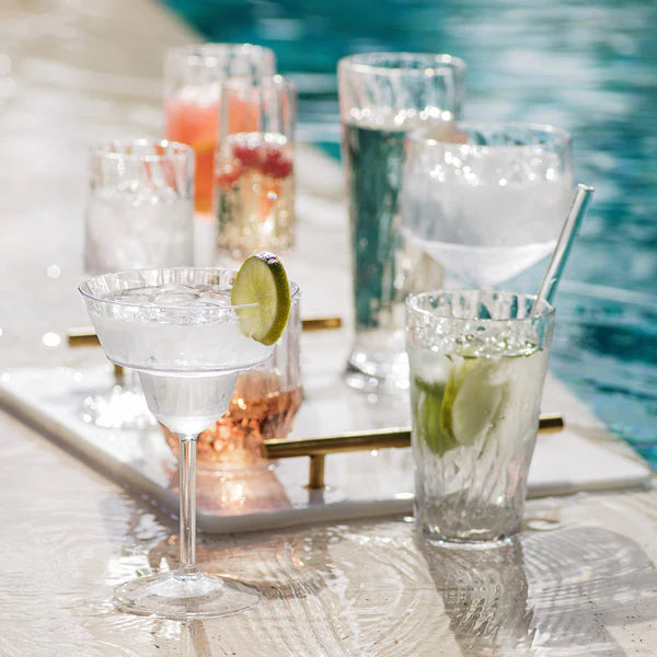 Cocktails with lime wedges on a tray by a pool