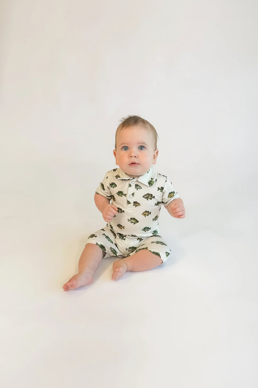 Baby wearing a patterned onesie on a plain background